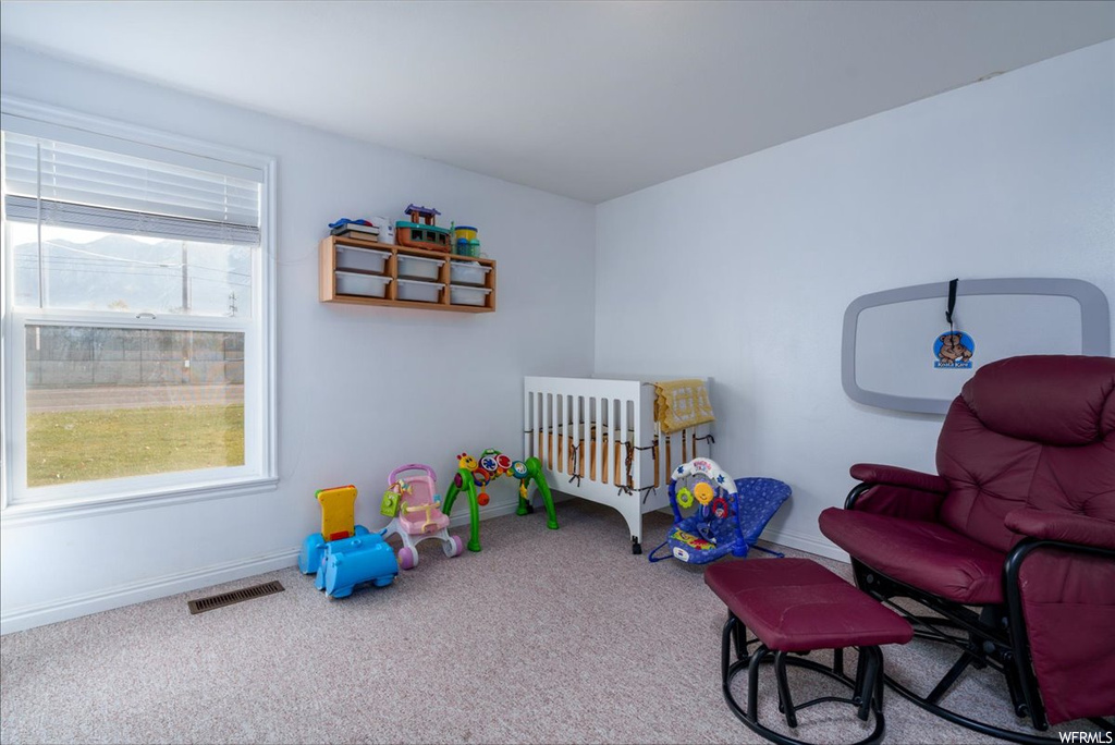 Bedroom featuring light colored carpet and a nursery area
