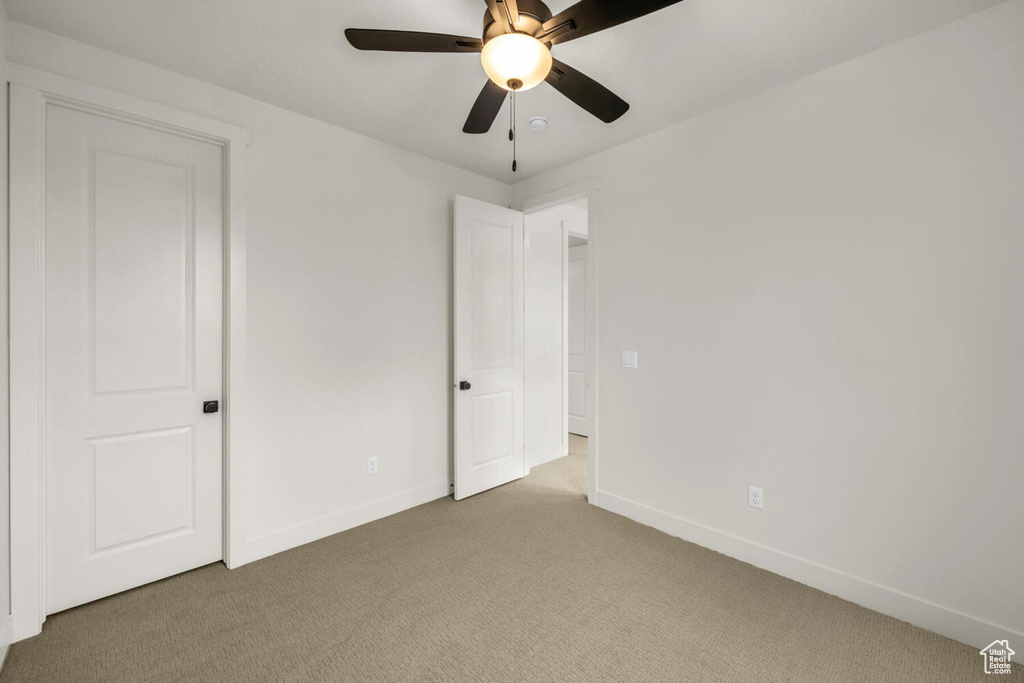 Unfurnished bedroom featuring ceiling fan and dark carpet