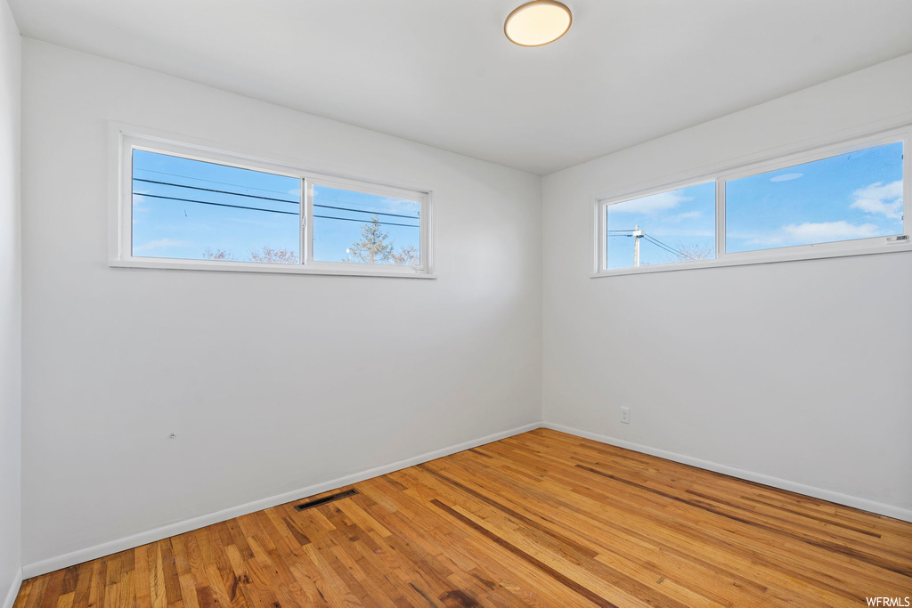 Unfurnished room featuring hardwood / wood-style floors and plenty of natural light