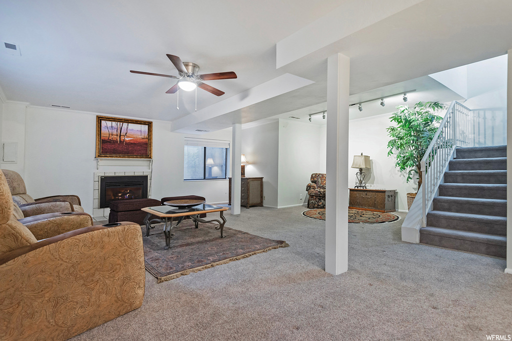 Living room featuring a tile fireplace, ceiling fan, rail lighting, and light carpet