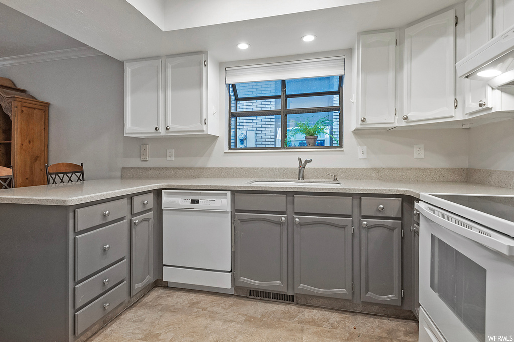 Kitchen with gray cabinets, white dishwasher, sink, and crown molding