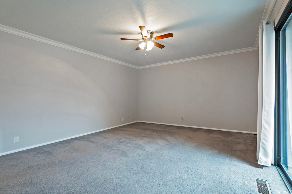 Carpeted empty room with ceiling fan and ornamental molding