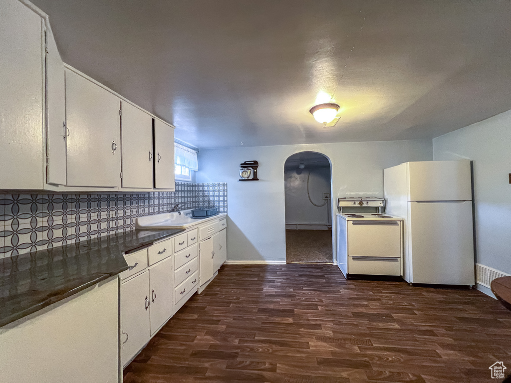 Kitchen featuring backsplash, wood-type flooring, white appliances, and white cabinets