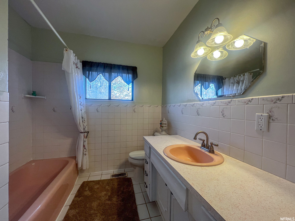 Full bathroom featuring shower / bathtub combination with curtain, tile floors, tile walls, and oversized vanity