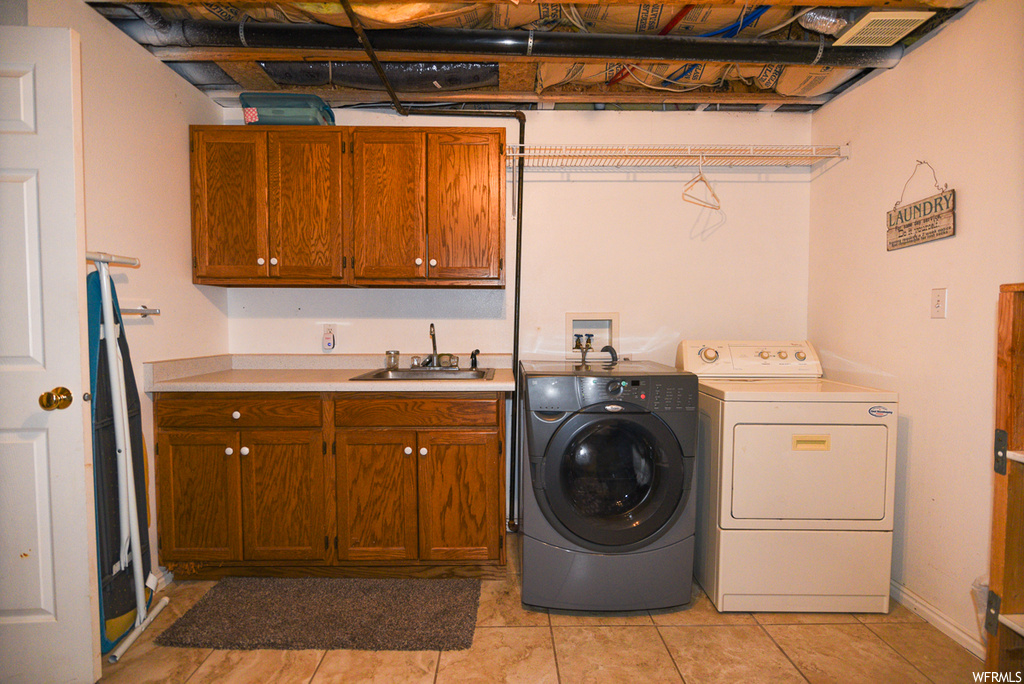 Laundry area featuring washer and clothes dryer, cabinets, sink, and light tile floors