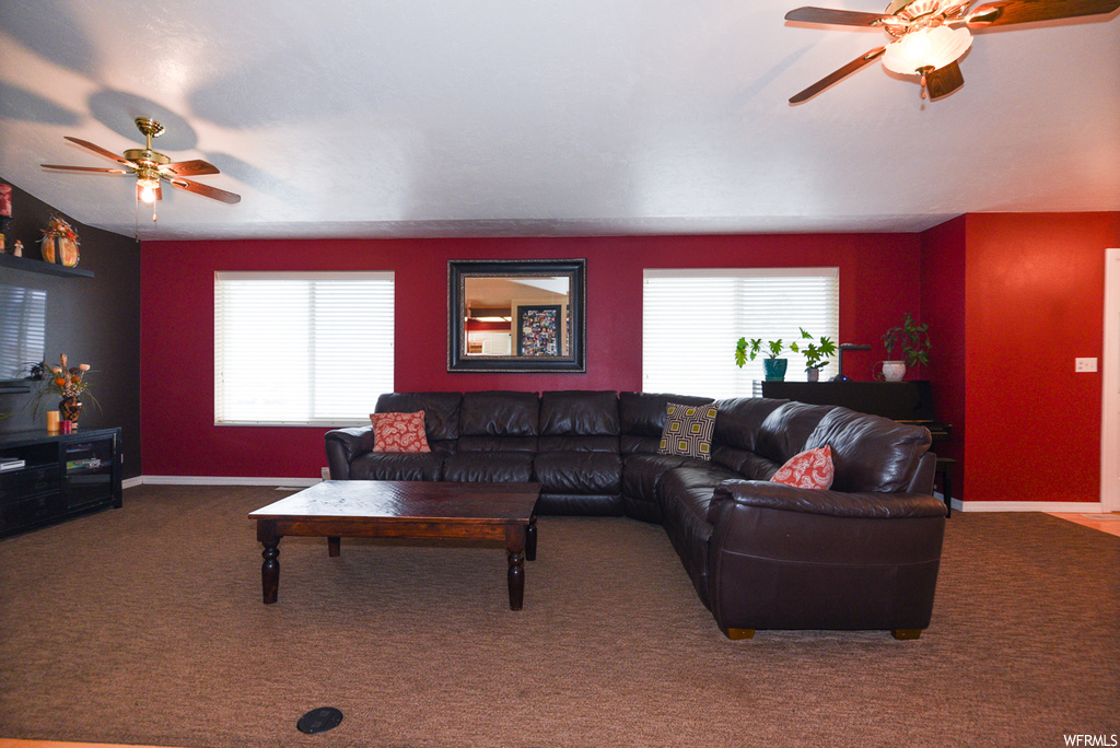 Carpeted living room featuring ceiling fan and a healthy amount of sunlight