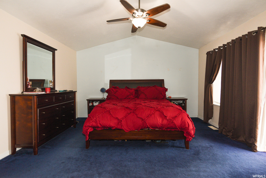 Bedroom with dark carpet, ceiling fan, and vaulted ceiling