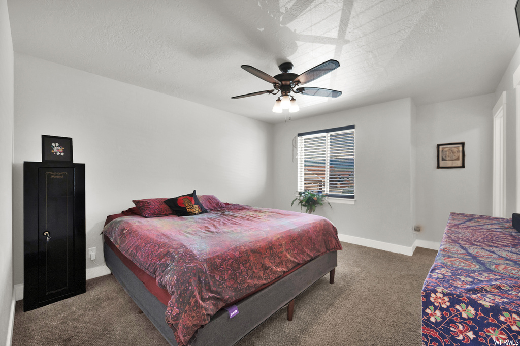 Bedroom featuring dark colored carpet, ceiling fan, and a textured ceiling
