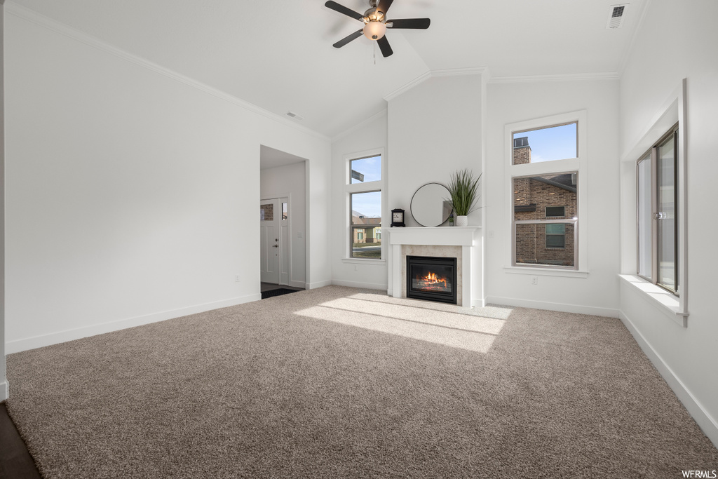 Unfurnished living room with ceiling fan, lofted ceiling, light carpet, and crown molding