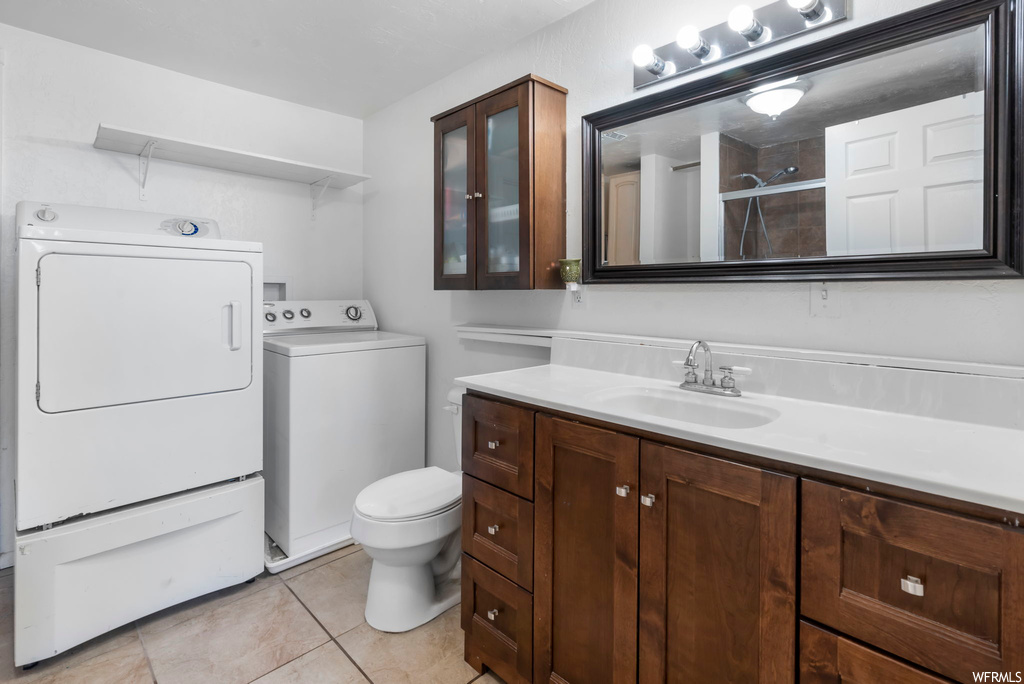 Bathroom with washing machine and clothes dryer, toilet, tile flooring, and vanity