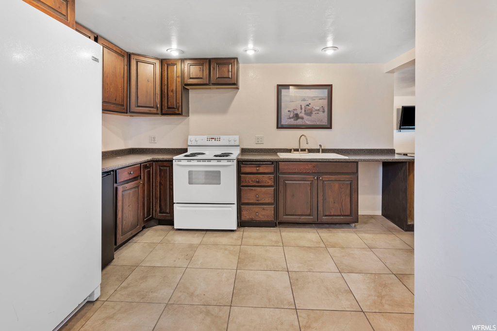 Kitchen featuring light tile flooring, sink, and white appliances