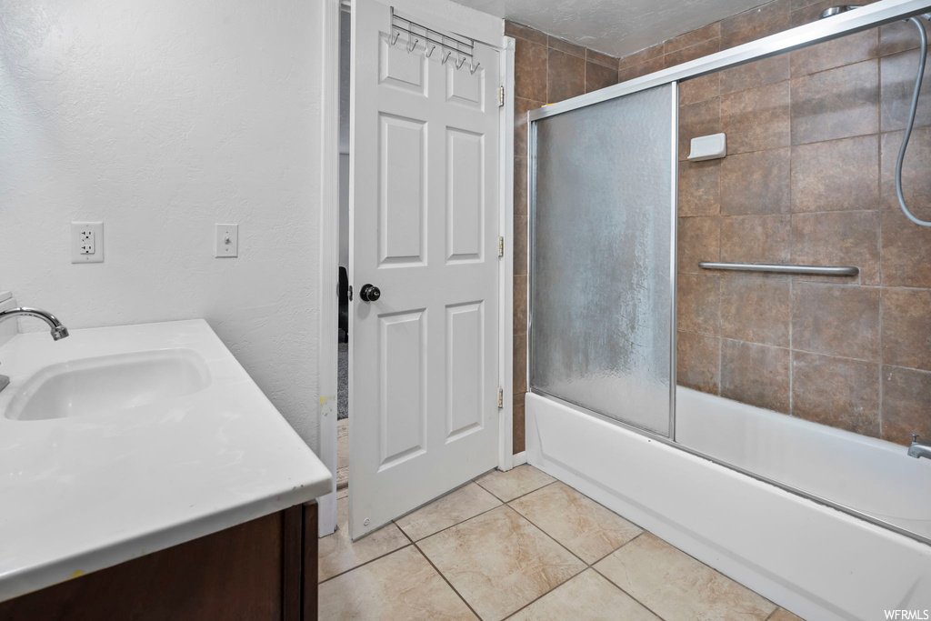 Bathroom with tile floors, combined bath / shower with glass door, and vanity