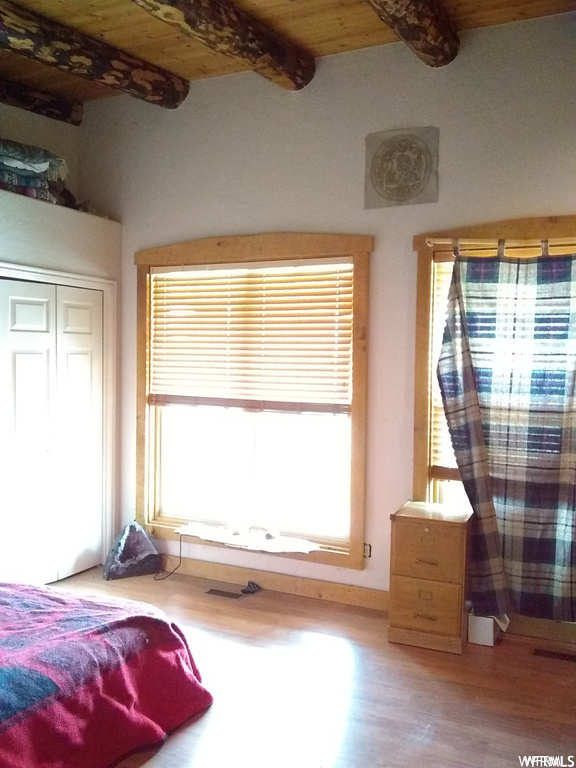 Bedroom featuring light wood-type flooring, beam ceiling, and multiple windows