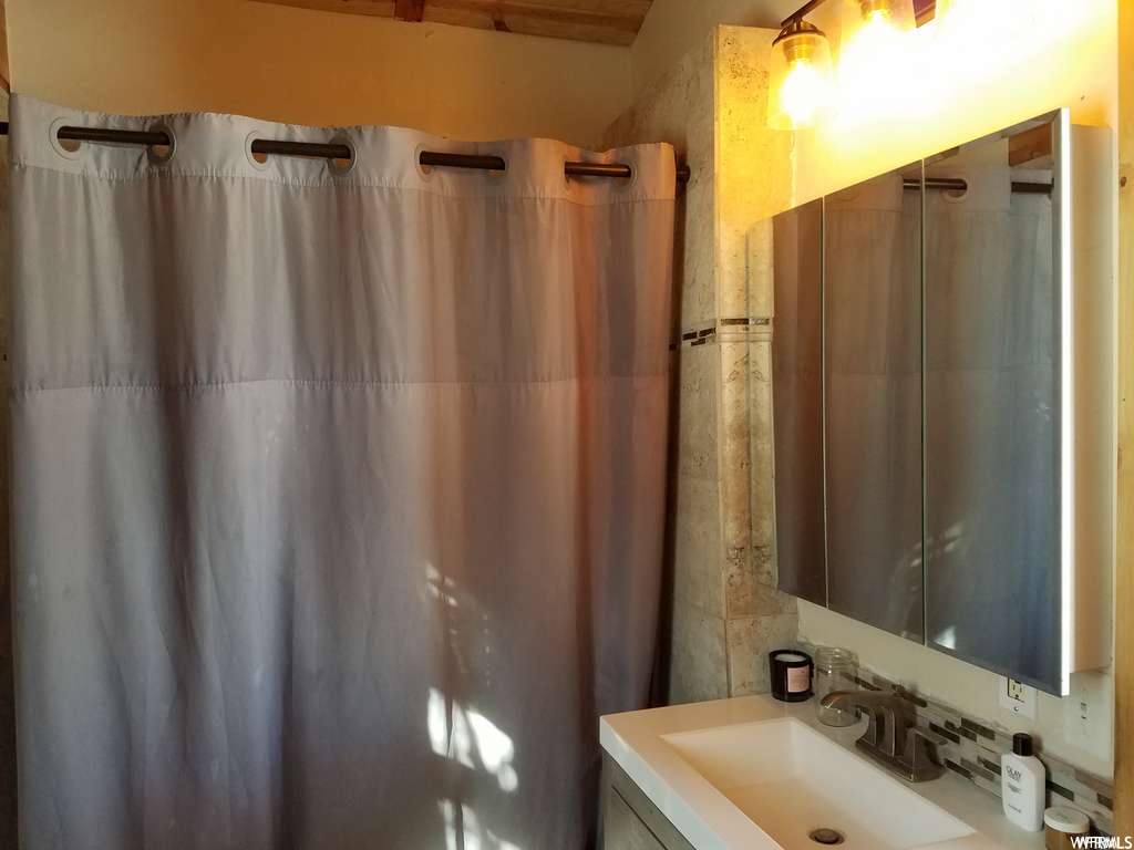 Bathroom featuring vanity, tile walls, and backsplash