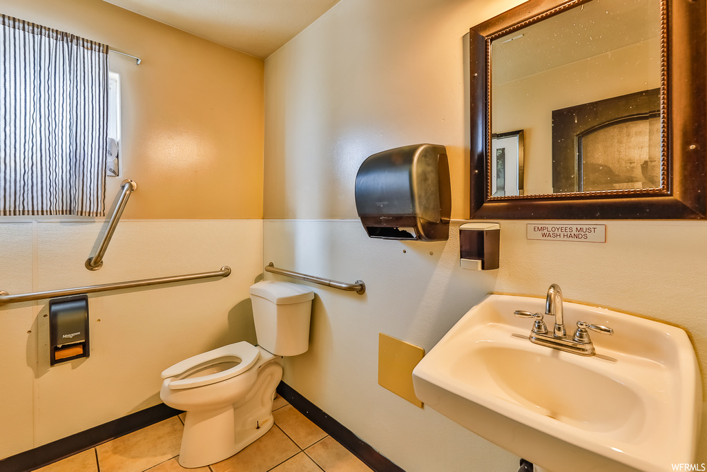 Bathroom with toilet, tile floors, and sink