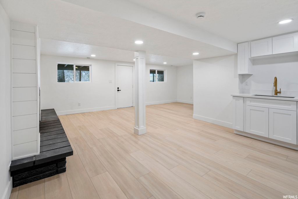 Basement featuring sink and light hardwood / wood-style flooring