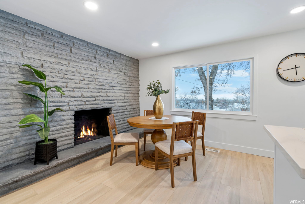 Dining area featuring a stone fireplace and light hardwood / wood-style floors
