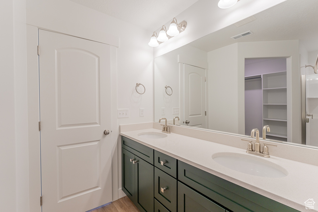 Bathroom featuring hardwood / wood-style floors, vanity with extensive cabinet space, and dual sinks