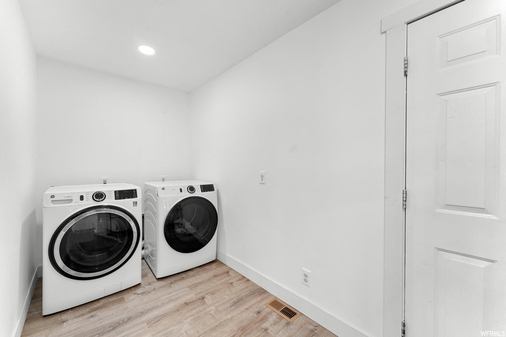Clothes washing area featuring light hardwood / wood-style flooring and washing machine and dryer