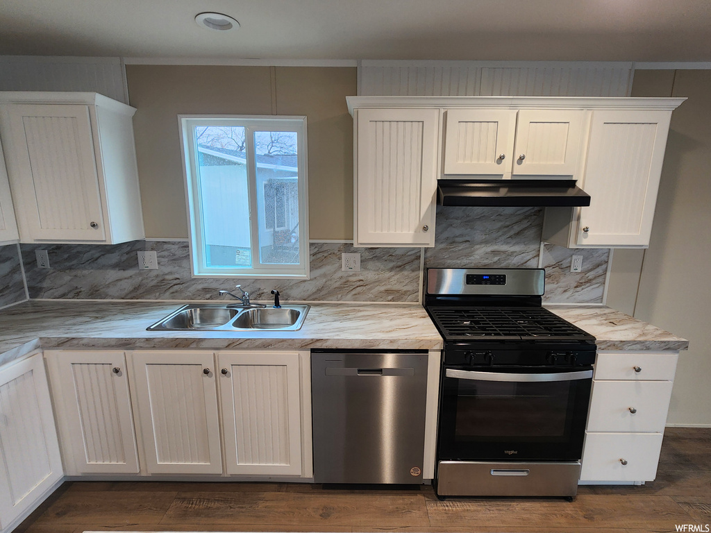 Kitchen with sink, tasteful backsplash, stainless steel appliances, white cabinets, and dark hardwood / wood-style floors