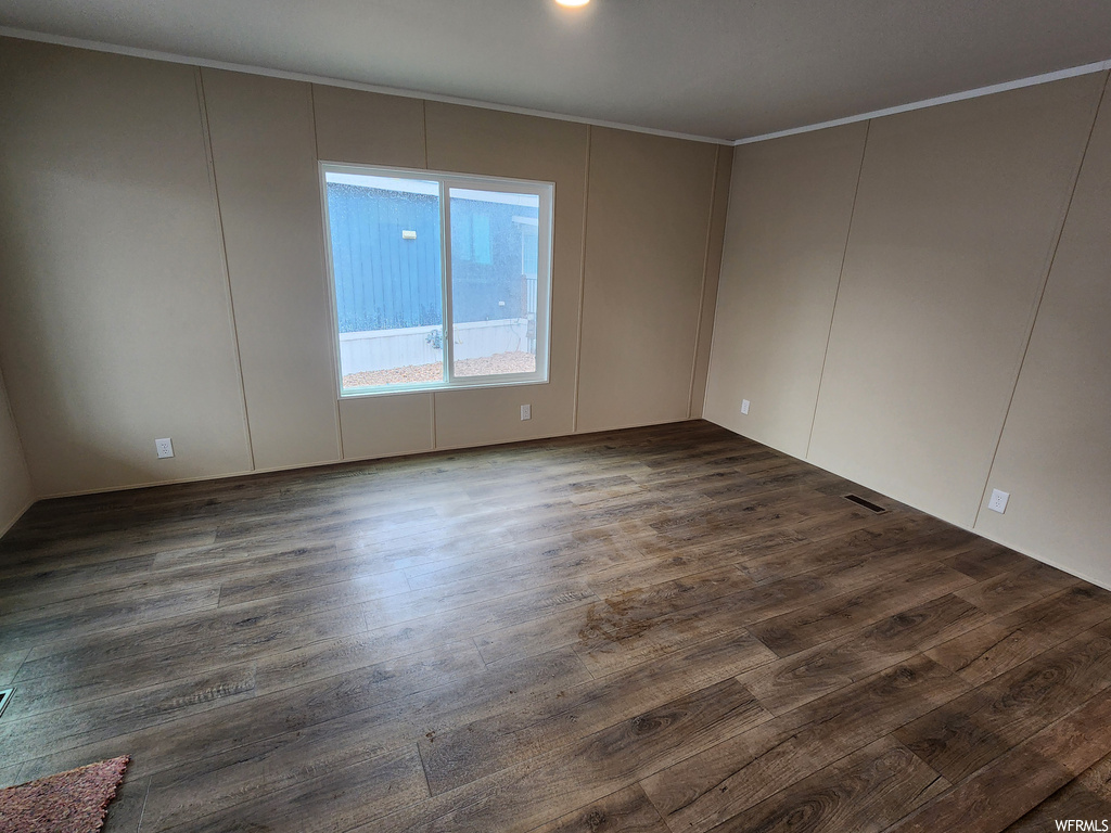 Spare room featuring dark hardwood / wood-style floors and crown molding