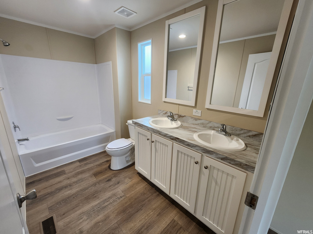Full bathroom with toilet, tub / shower combination, hardwood / wood-style flooring, dual bowl vanity, and ornamental molding