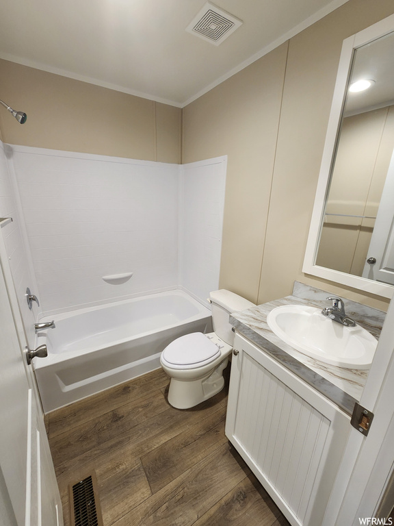Full bathroom with bathing tub / shower combination, toilet, hardwood / wood-style floors, and vanity