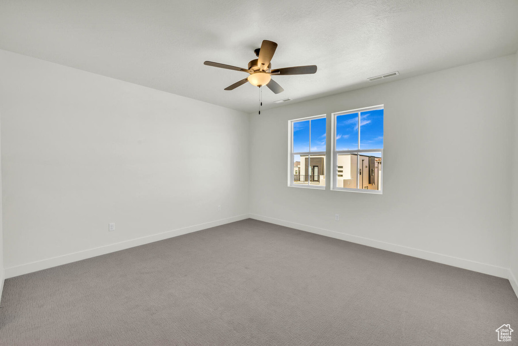 Carpeted spare room featuring ceiling fan