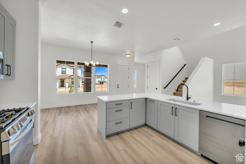 Kitchen featuring gray cabinets, stainless steel appliances, sink, and light hardwood / wood-style flooring