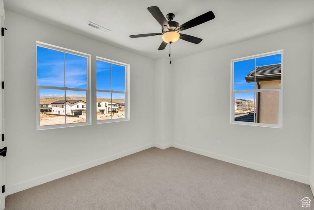 Carpeted empty room featuring ceiling fan