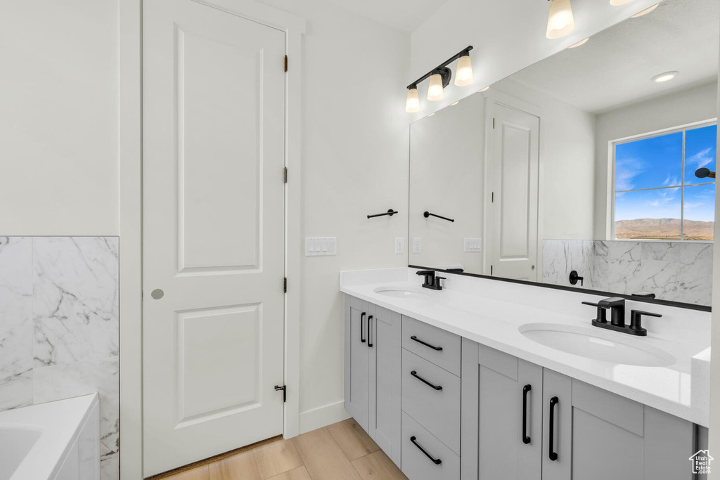 Bathroom featuring a tub to relax in, hardwood / wood-style flooring, and vanity