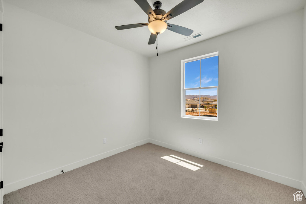 Carpeted spare room featuring ceiling fan