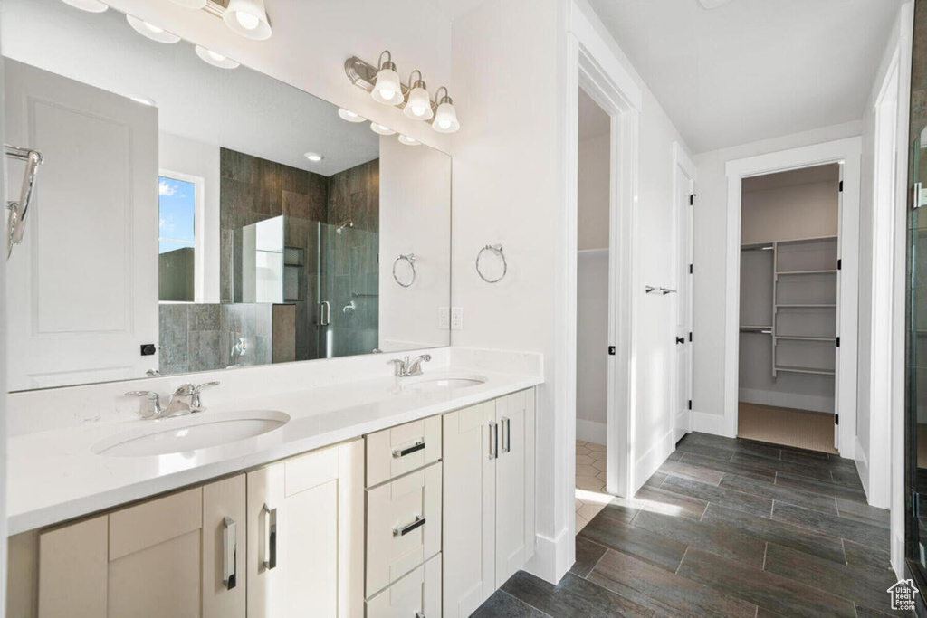 Bathroom featuring tile floors, dual vanity, and walk in shower