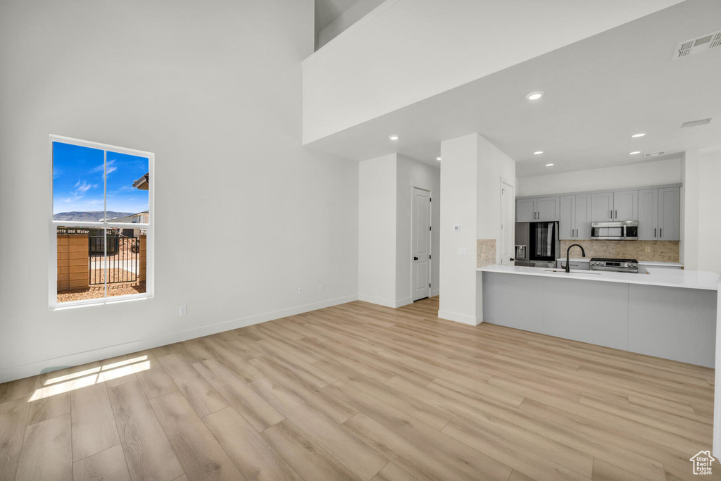 Unfurnished living room featuring light hardwood / wood-style flooring and sink