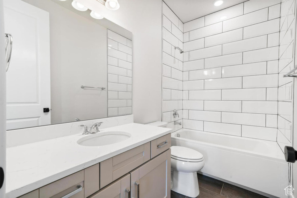 Full bathroom featuring tiled shower / bath, toilet, vanity with extensive cabinet space, and tile flooring