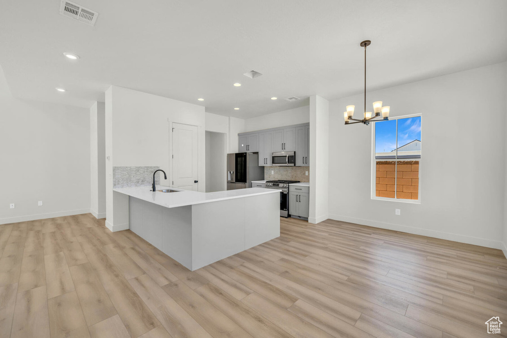 Kitchen with stainless steel appliances, kitchen peninsula, light wood-type flooring, and sink