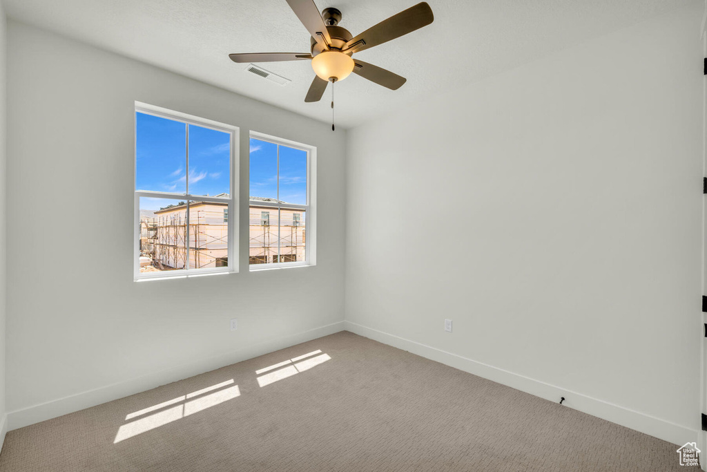 Carpeted empty room featuring ceiling fan