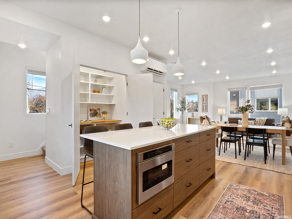 Kitchen featuring a center island, hanging light fixtures, light wood-type flooring, and stainless steel appliances
