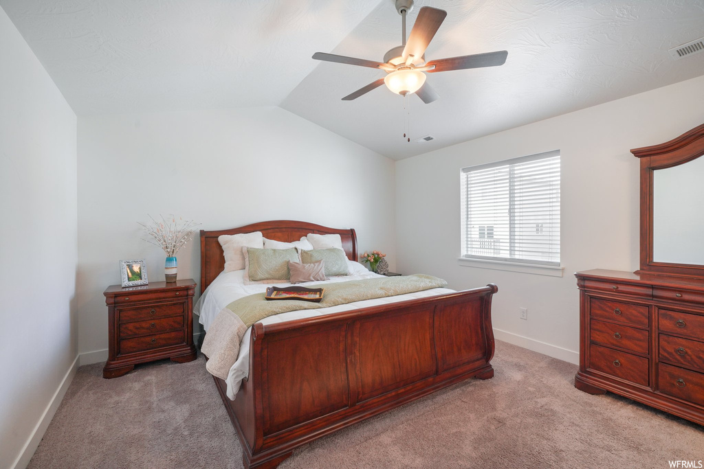 Bedroom featuring lofted ceiling, ceiling fan, and light colored carpet