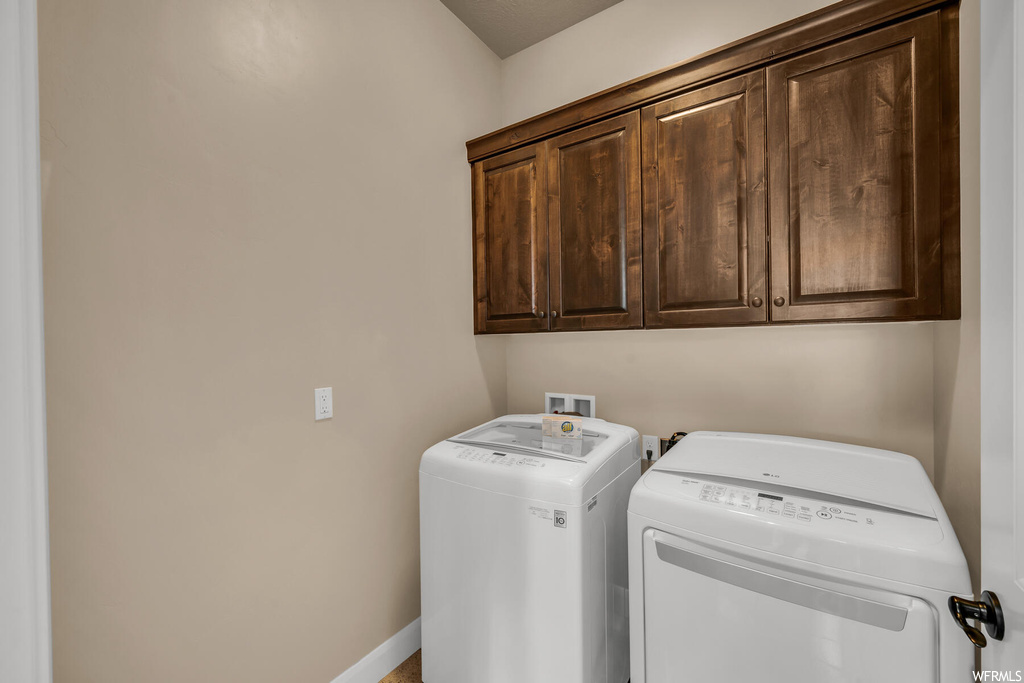 Laundry area with washing machine and clothes dryer, cabinets, and washer hookup