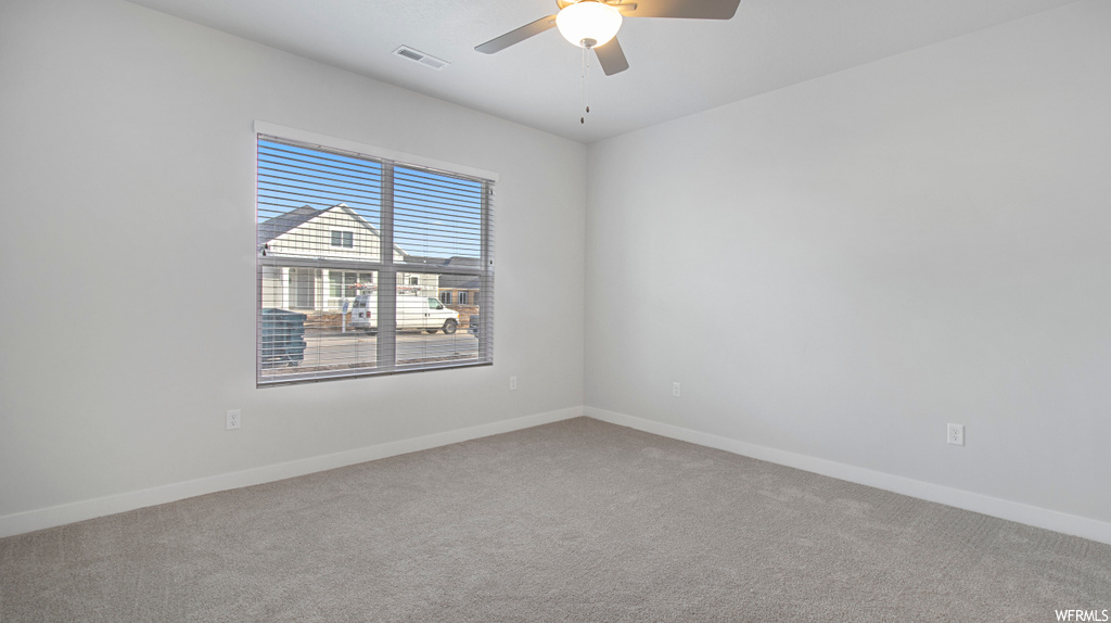 Empty room featuring ceiling fan and light colored carpet