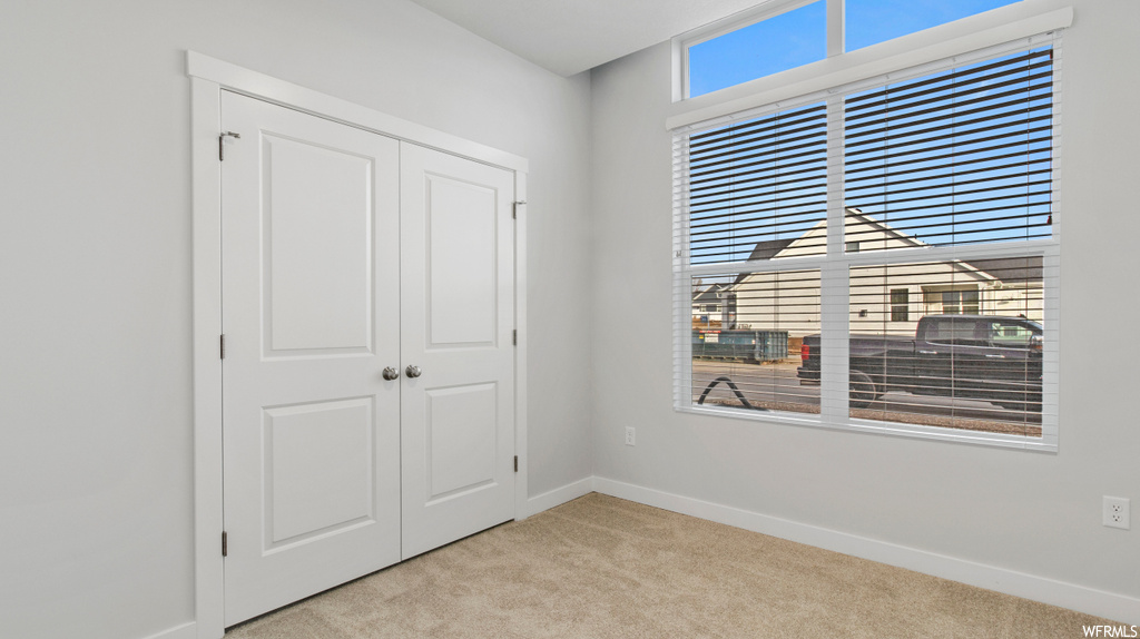 Unfurnished bedroom with light colored carpet, a closet, and multiple windows