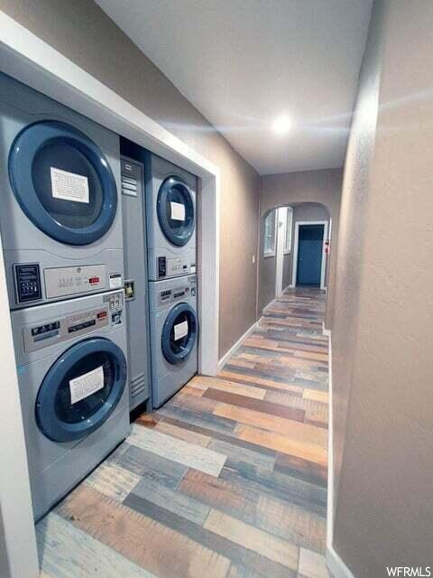 Clothes washing area with stacked washer and clothes dryer and light wood-type flooring