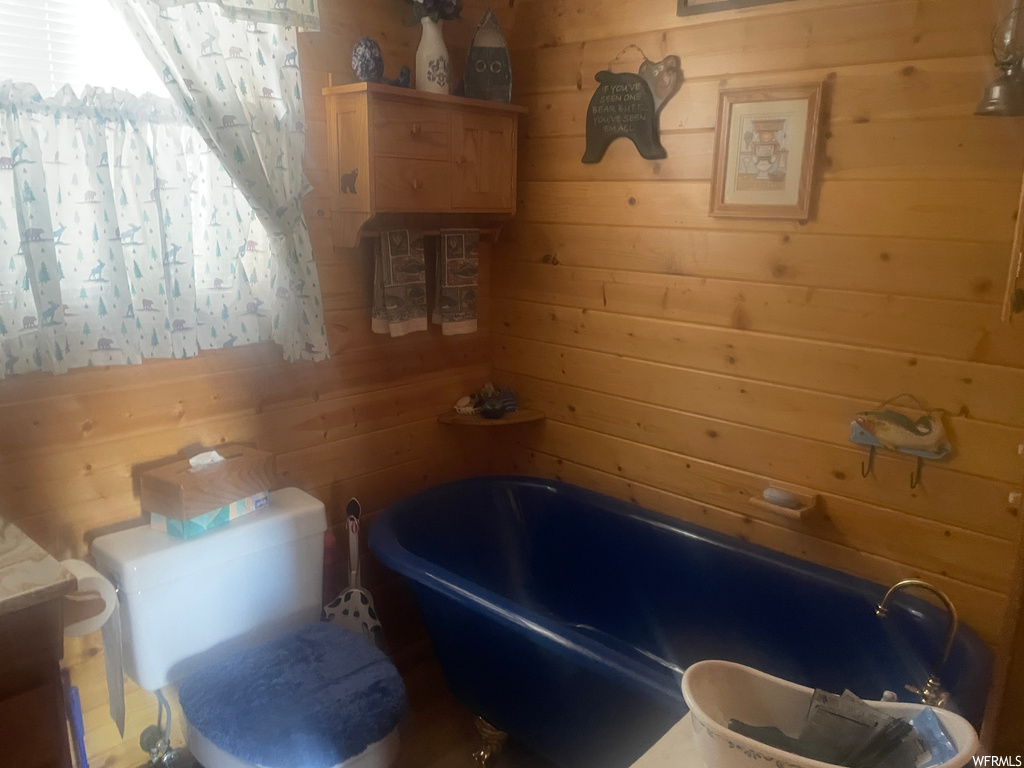 Bathroom featuring toilet, wooden walls, and a washtub