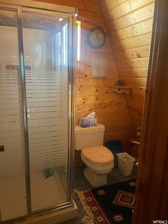 Bathroom with lofted ceiling, wooden walls, toilet, and wooden ceiling