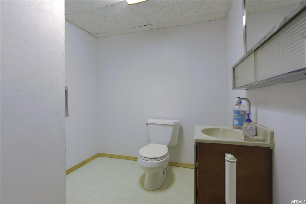 Bathroom with toilet, tile floors, a paneled ceiling, and vanity
