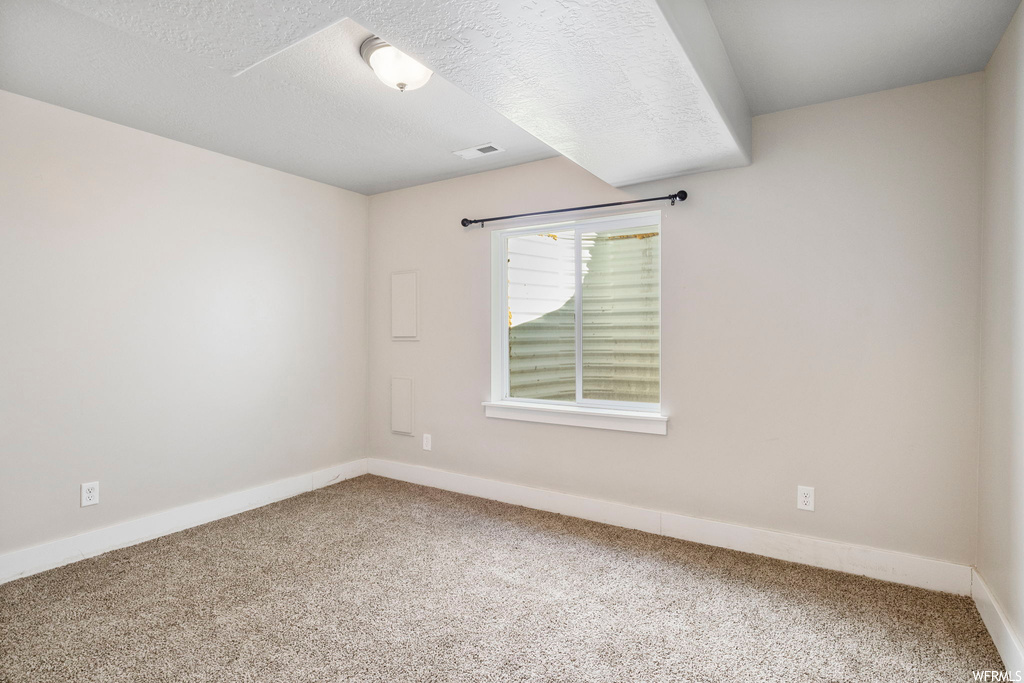 Spare room with light colored carpet and a textured ceiling
