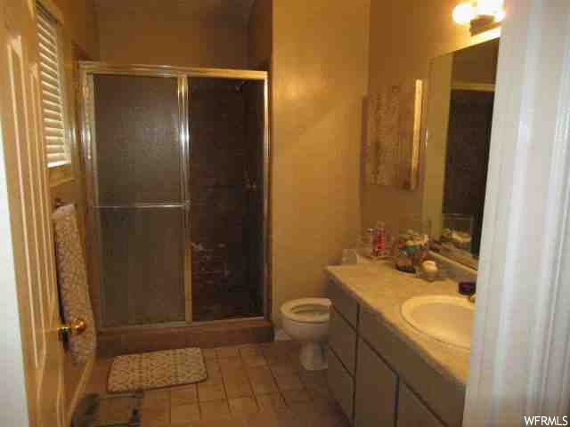 Bathroom featuring vanity, mirror, a shower with door, and light tile floors