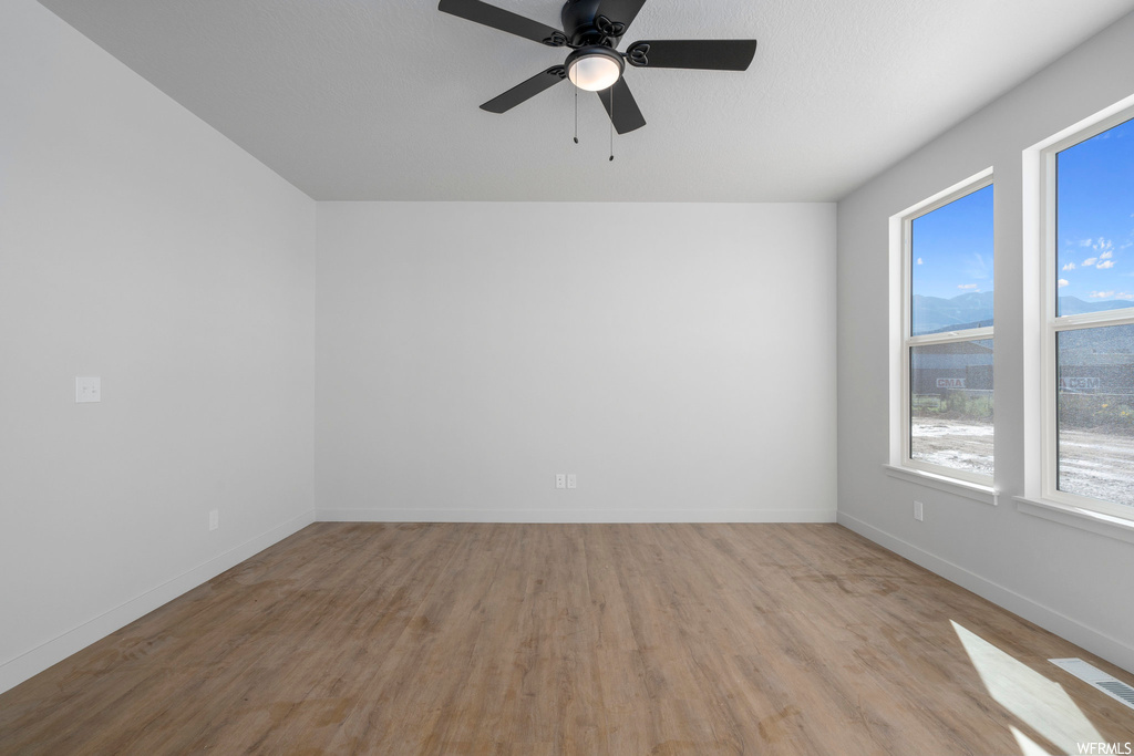 Empty room featuring light wood-type flooring and ceiling fan