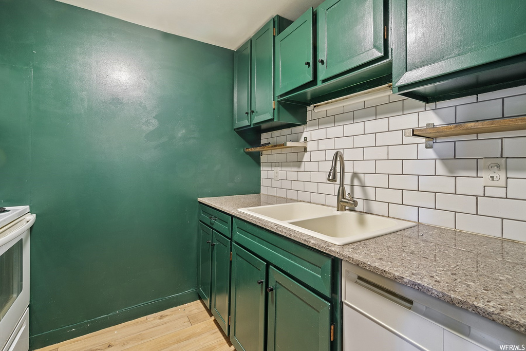 Kitchen with sink, light hardwood / wood-style floors, stove, dishwasher, and tasteful backsplash